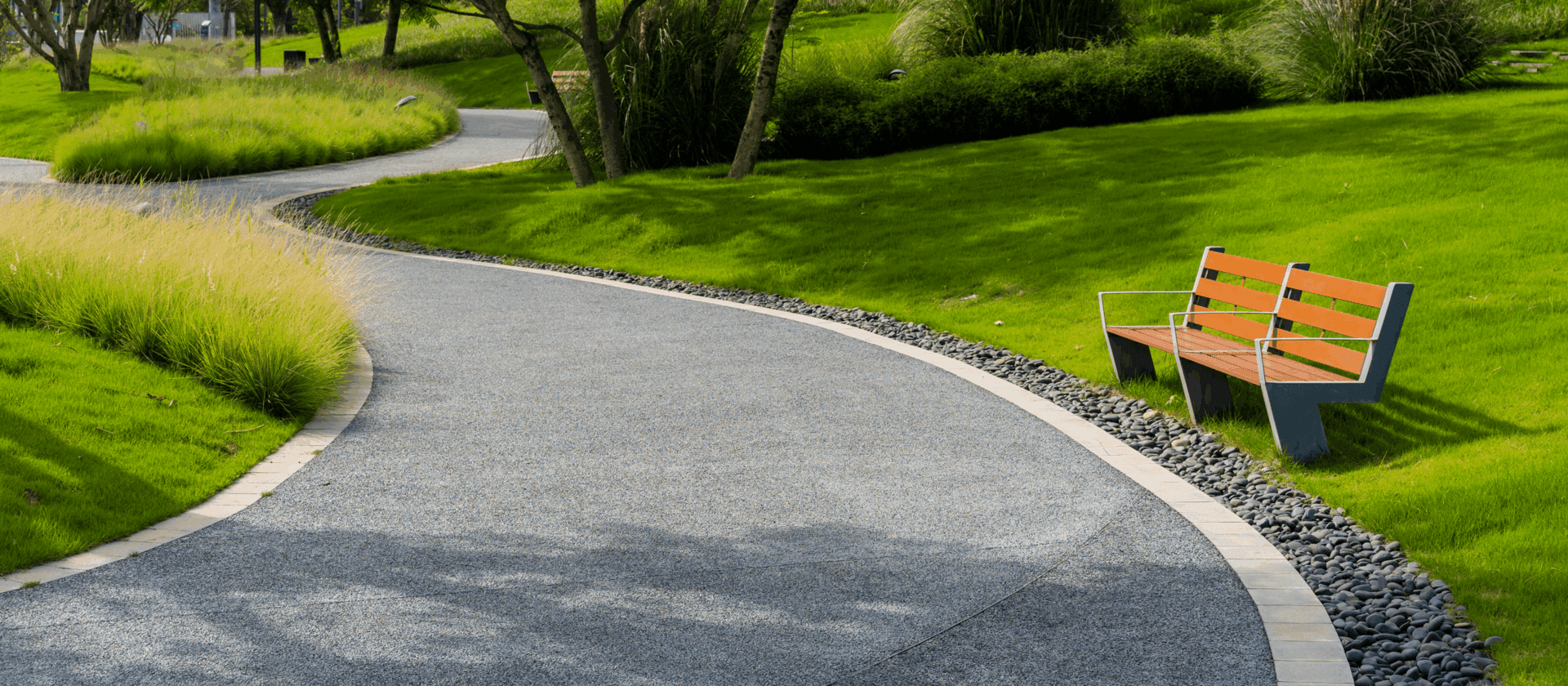 Curved path with bench in green park.